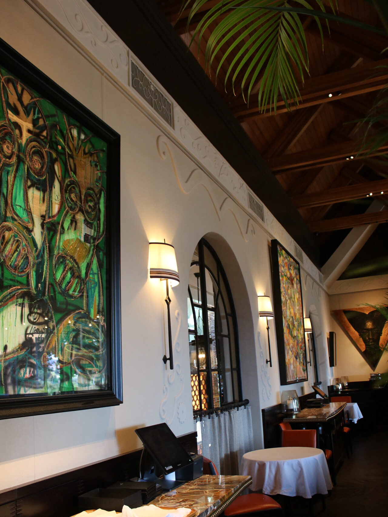 Delaire Graff dining room with hand-sculpted plaster scrollwork detailing along the cornice and wall panels, framed by an arched window overlooking the wine cellar tanks