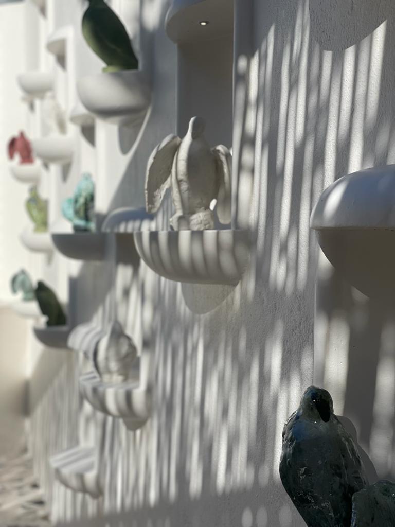 La Colombe entrance with hand-formed plaster niches by Plaster Art SA lining the walls, each displaying a colourful bird sculpture